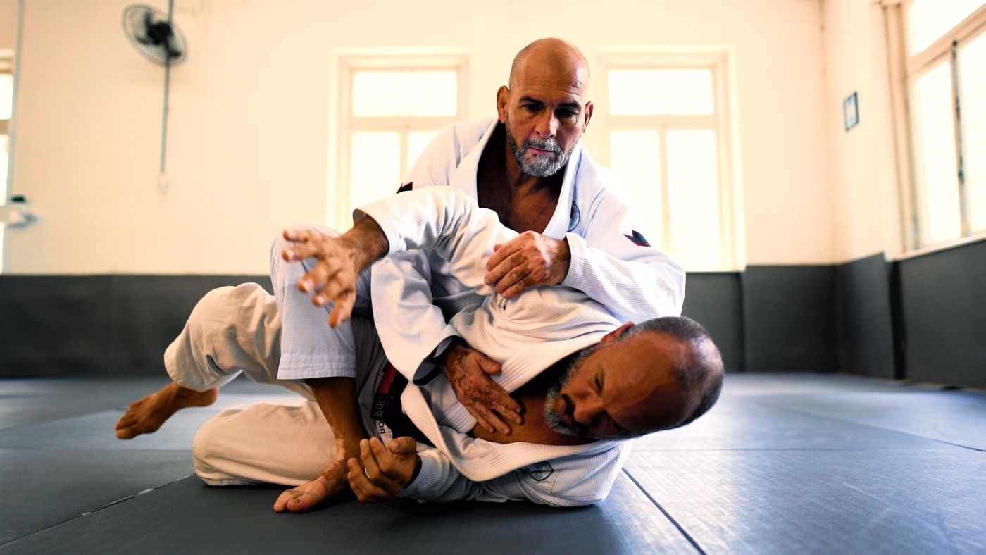 Dois praticantes demonstrando uma técnica de jiu-jitsu no tatame